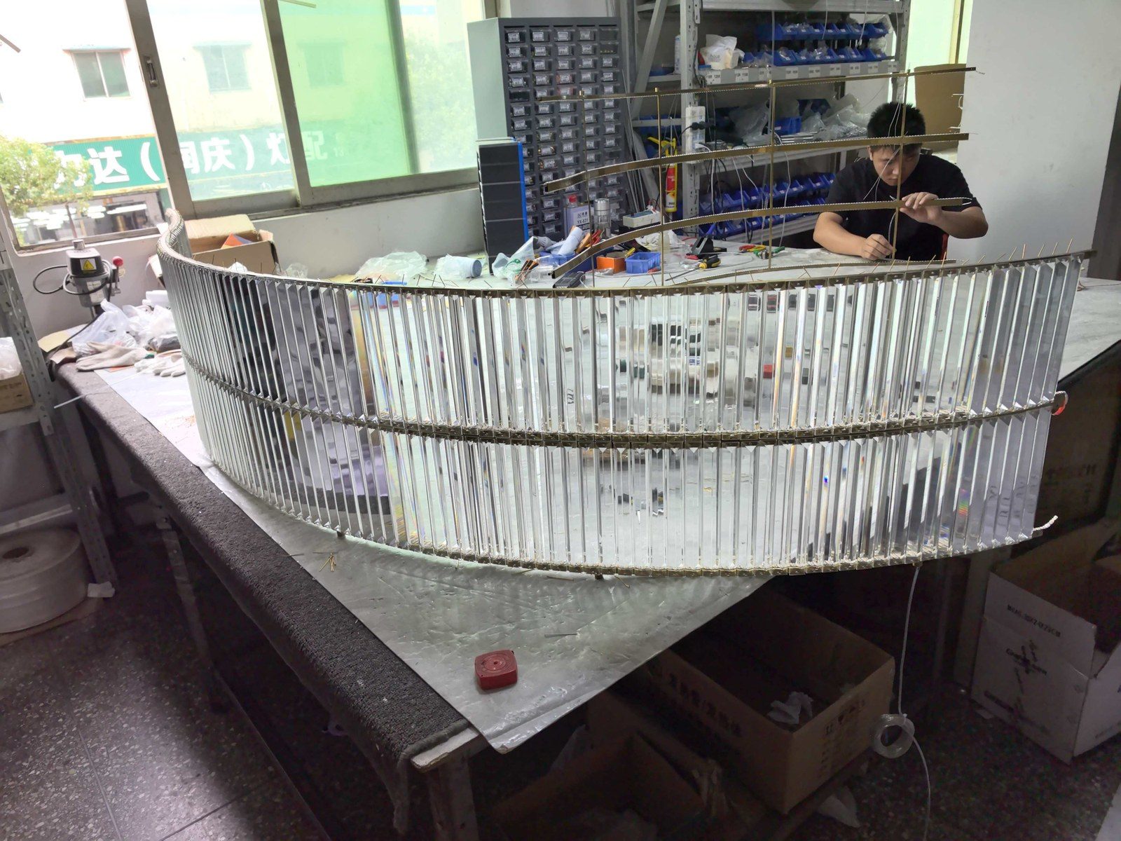 Factory worker assembling a custom large-format chandelier frame at the Staylighting workshop.